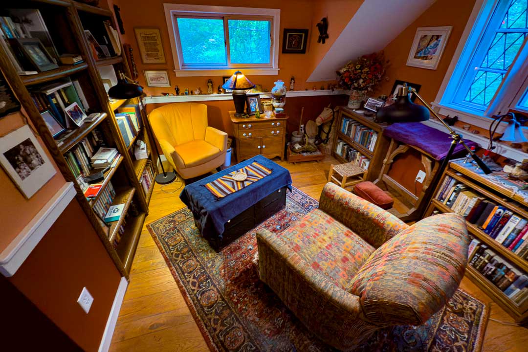 A reading room with everything in its place. There are two easy chairs, lots of book shelves and lamps.